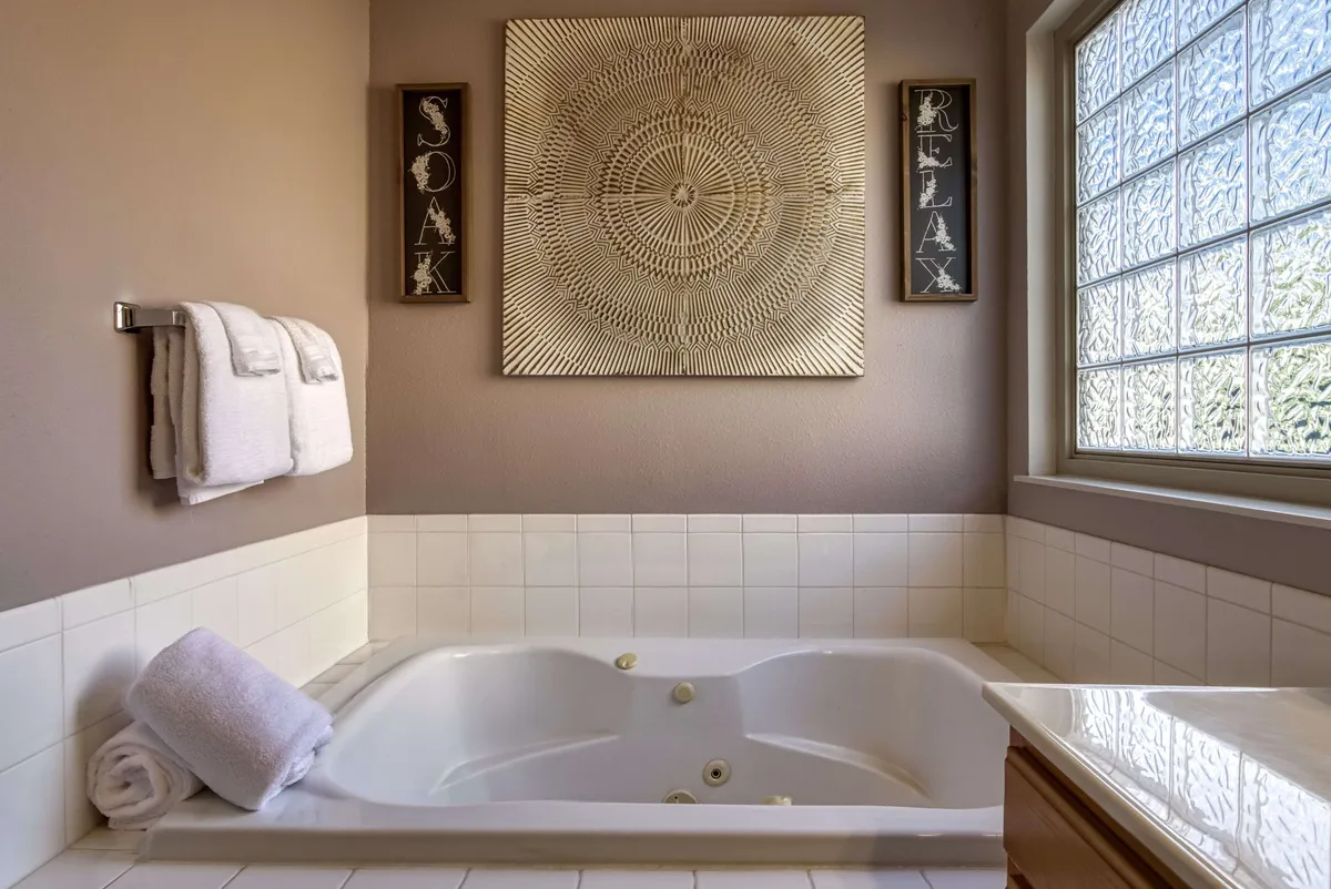 A relaxing bathroom featuring a jacuzzi tub, tasteful wall art, and neatly arranged towels on a rack. The mood is spa-like and luxurious, offering a quiet sanctuary for self-care and relaxation.