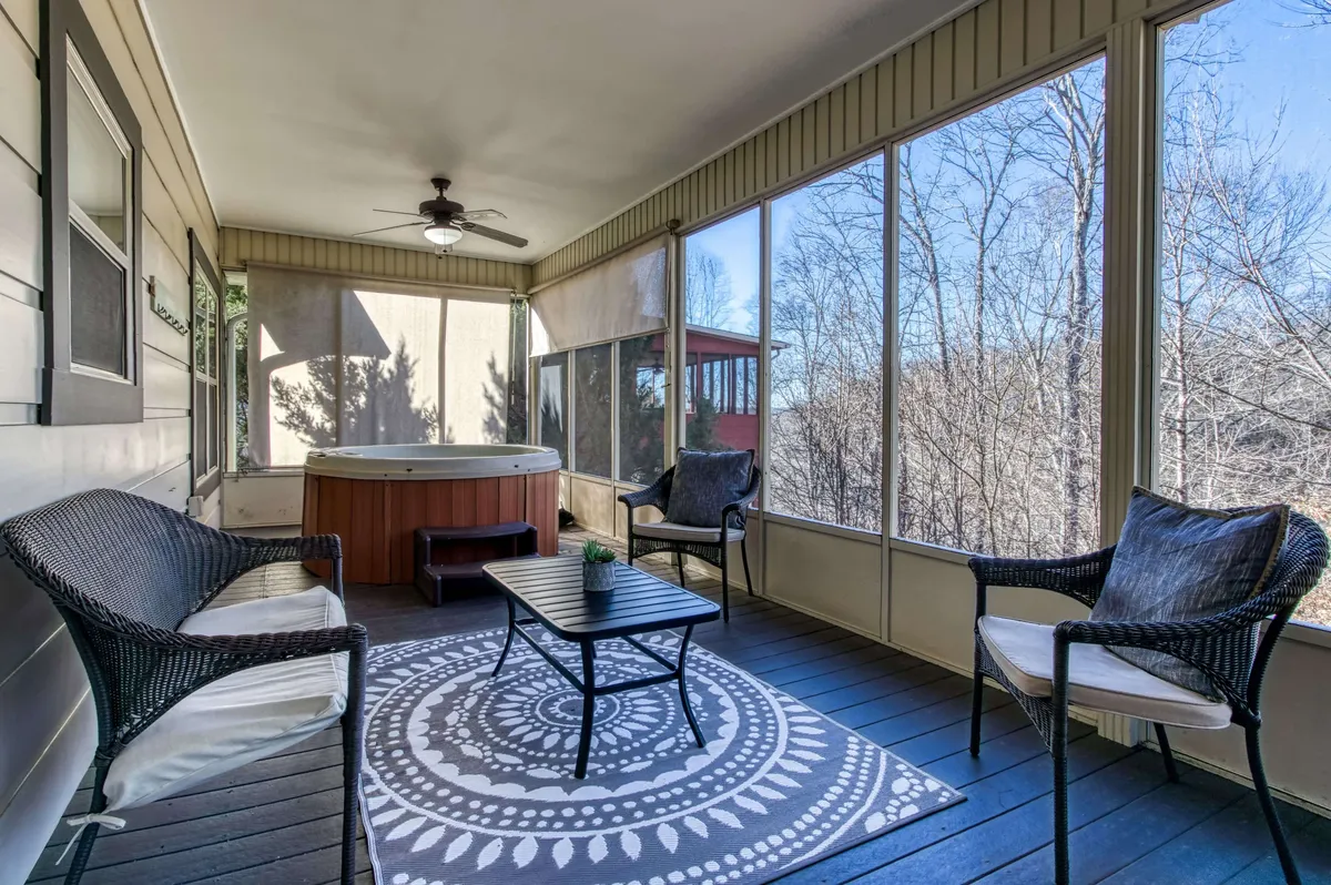A tranquil interior view highlighting a hot tub and seating area, with a decorative rug and gentle natural light. The design encourages both relaxing soaks and connection with nature through the porch’s openness.