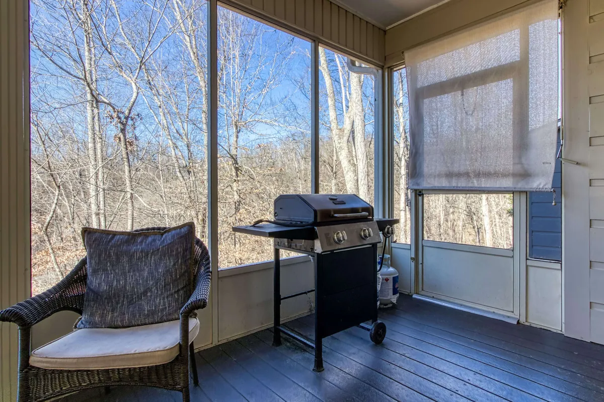 A tranquil indoor-outdoor space with a grill and armchair framed by large windows, seamlessly blending relaxation with scenic views. The setup hints at enjoying barbecues, quiet moments, and special occasions while still being connected to the natural world outside.